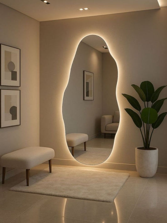 Modern interior with a large oval mirror, bench, and plant in a well-lit room.