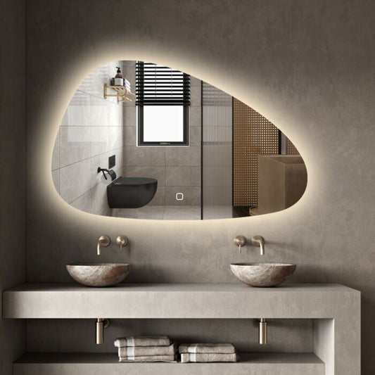 Bathroom vanity with two stone sinks, a large illuminated mirror, and towels on a shelf.