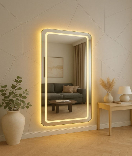 Large illuminated wall mirror in a living room setting with a couch and decor.