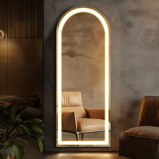 Modern floor mirror with LED lighting reflecting a room with a sofa and plant.