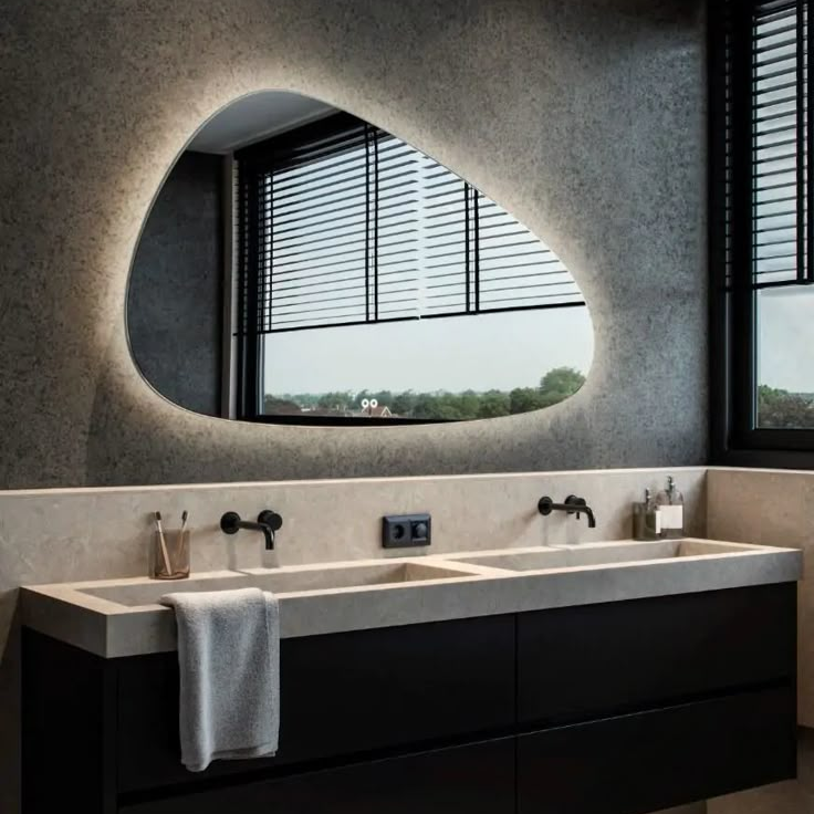 Modern bathroom with a large oval mirror and black vanity.