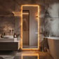 Modern bathroom with a large illuminated mirror and marble walls.