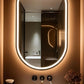Bathroom with a large oval mirror with lights, sink, and decorative elements.