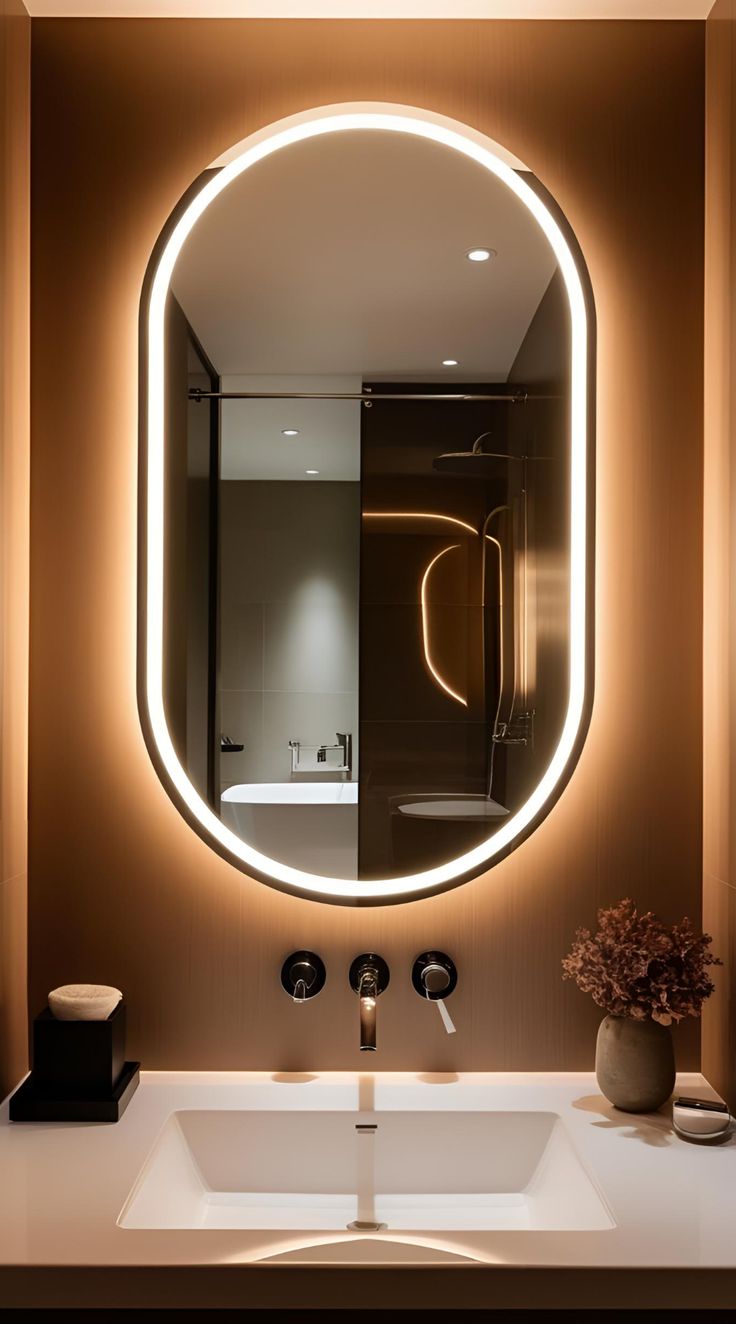 Bathroom with a large oval mirror with lights, sink, and decorative elements.
