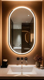 Bathroom with a large oval mirror with lights, sink, and decorative elements.