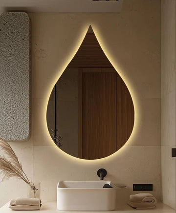 Modern bathroom with a teardrop-shaped mirror emitting a warm glow.