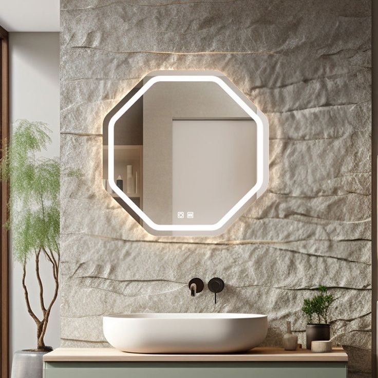Bathroom vanity with a modern lighted mirror on a stone wall.