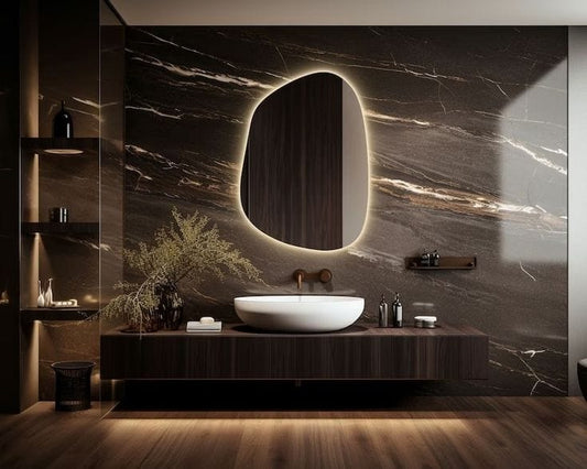Modern bathroom with a marble wall, illuminated mirror, and wooden vanity.