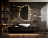 Modern bathroom with a marble wall, illuminated mirror, and wooden vanity.