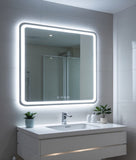 Bathroom vanity with illuminated mirror, sink, and decorative plants.