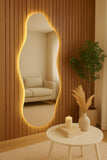 Decorative mirror with a wooden frame and LED lighting in a room with a sofa and table.