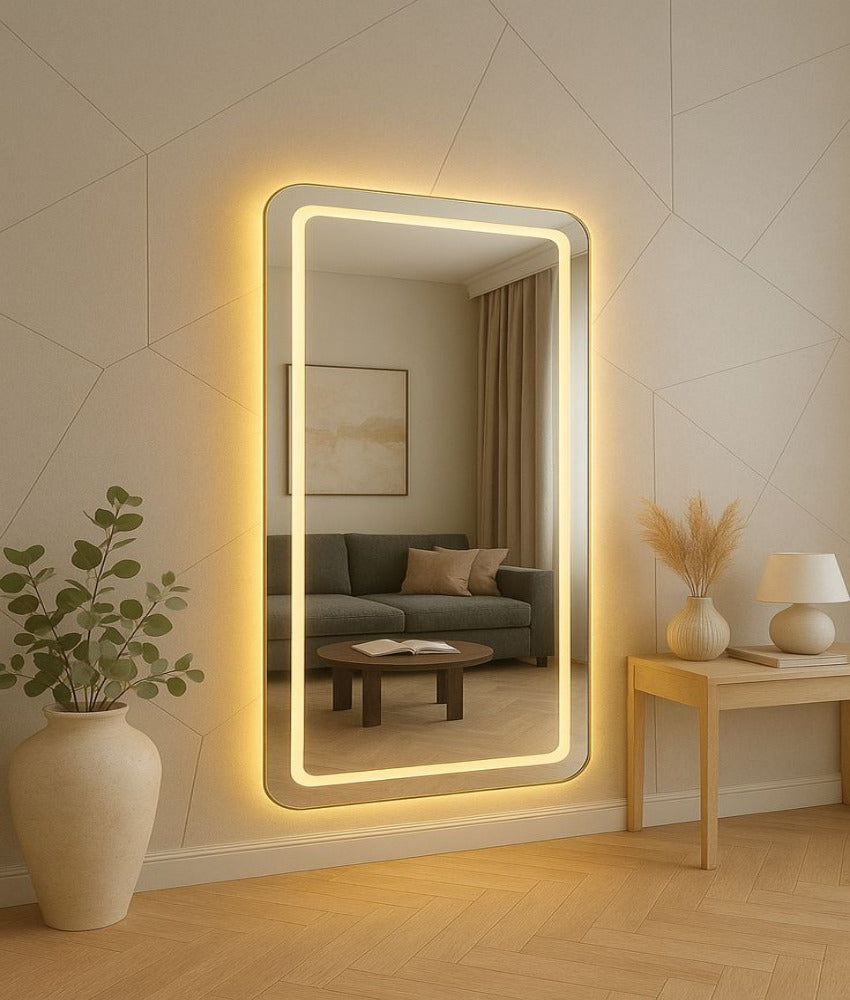 Large illuminated wall mirror in a living room setting with a couch and decor.