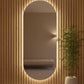 Oval mirror with LED lighting on a wooden wall next to a potted plant