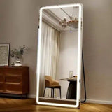 Large illuminated floor mirror in a room with furniture and decor.